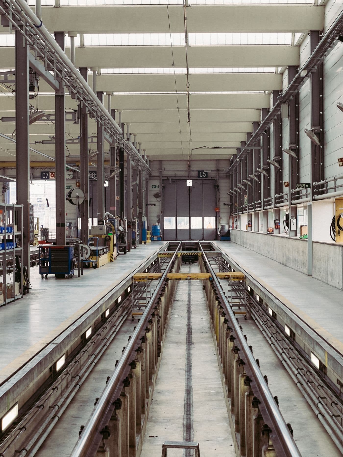 Long, clean industrial production hall with rails and service pits running down the centre