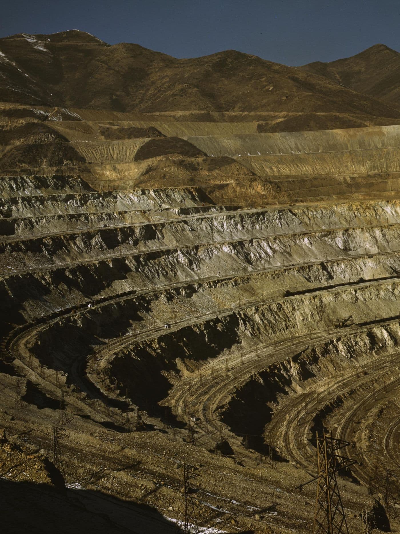 Terraced benches of a vast open-pit copper mine in warm evening light