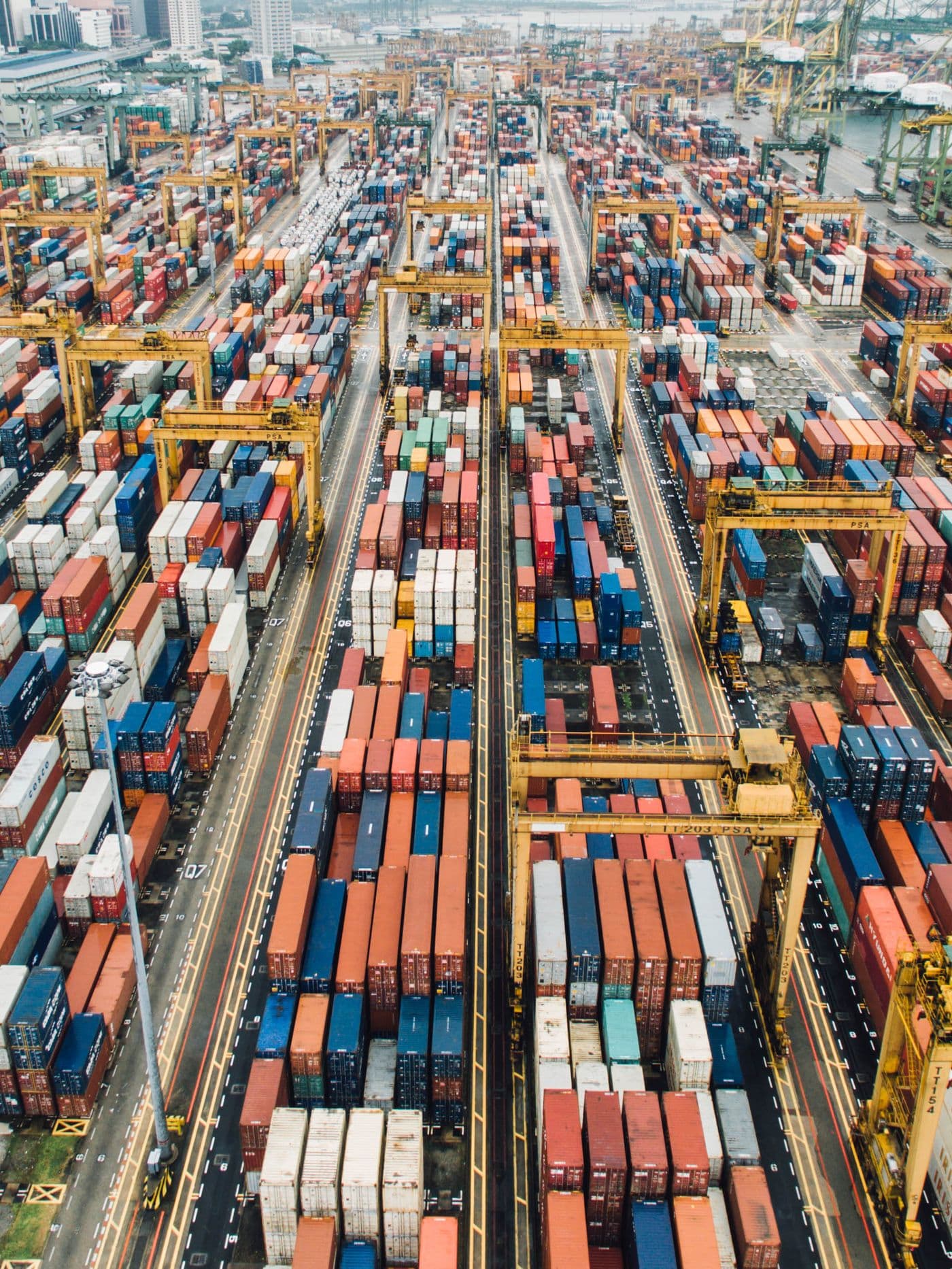 Aerial view of a container terminal with long rows of stacked containers and gantry cranes