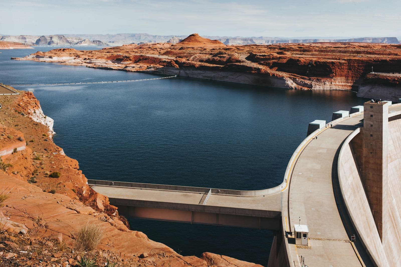 Concrete arch dam holding back a deep blue reservoir among red sandstone cliffs
